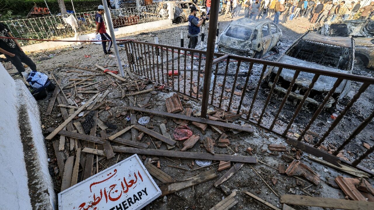 People search through debris outside the site of the Ahli Arab hospital in Gaza City on October 18, 2023 in the aftermath of an overnight strike there. 