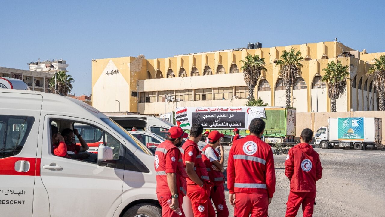 Medics and a convoy of trucks loaded with aid supplies for Gaza provided by Egyptian NGOs wait for an agreement to cross through the Egypt-Gaza border 