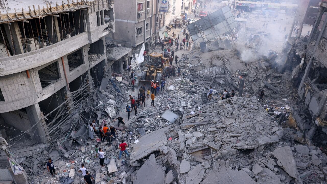 Palestinian civilians and rescuers help clear the rubble in the heavily bombarded city center of Khan Yunis in the southern Gaza Strip following Israeli strikes 