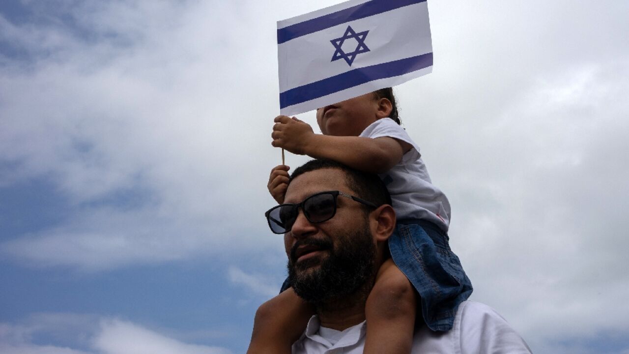 A man carrying a child on his shoulders demonstrates along Copacabana beach in Rio de Janeiro, Brazil, on October 15, 2023 A man carrying a child on his shoulders demonstrates along Copacabana beach in Rio de Janeiro, Brazil, on October 15, 2023
