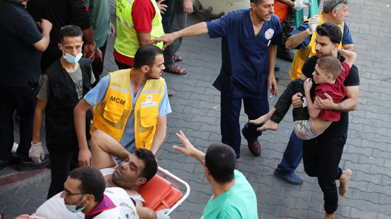 A man carries a wounded child into Gaza's Al-Shifa hospital following Israeli strikes on the coastal enclave on Tuesday