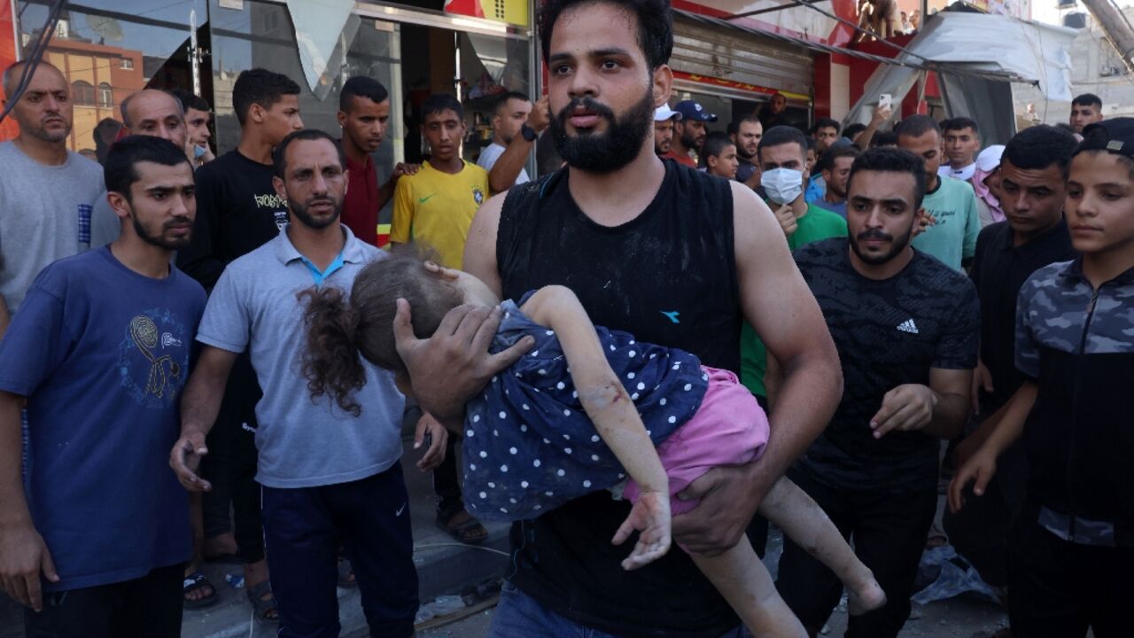 A man carries an injured girl after an Israeli strike on the Rafah refugee camp in the southern Gaza Strip on Wednesday. Israel's retaliatory bombardment of Gaza has killed over 6,500 people