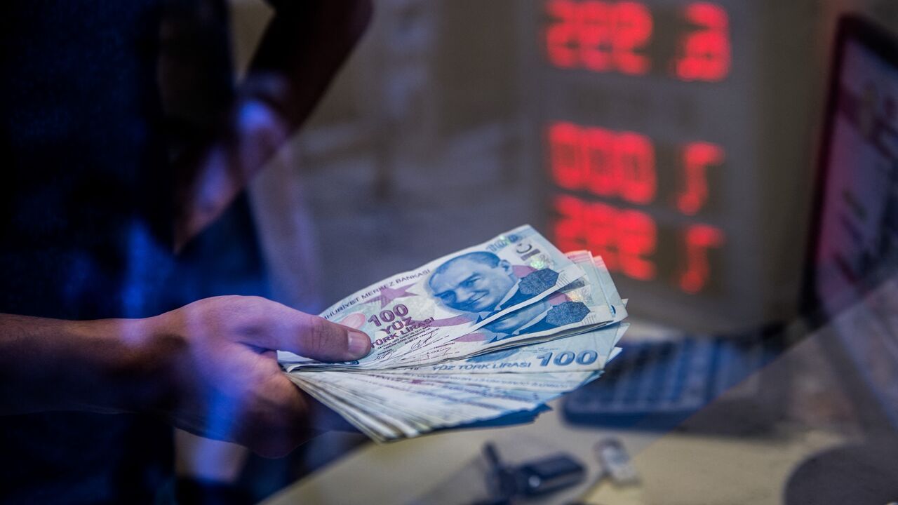 A teller holds Turkish lira banknotes at a currency exchange office, Istanbul, Aug. 13, 2018.