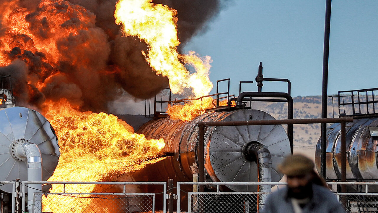 A man walks close to a fire raging at the Zarba oil facility in al-Qahtaniyah in northeastern Syria close to the Turkish border on October 5, 2023. Turkish strikes on October 5 on the Kurdish-controlled region of Hasakeh in northeastern Syria hit a car, killing two people, the Syrian Observatory for Human Rights said, after Ankara had threatened raids in retaliation for a bomb attack. In another strike, "Turkish drones targeted a factory north of Hasakeh, injuring three workers", said Farhad Shami, the spok