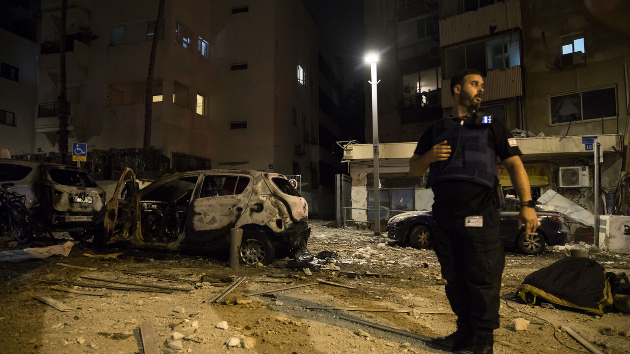 : Israeli security forces stand near a burned car at a scene where a rocket fired from Gaza strip hit a building on October 7, 2023 in Tel Aviv, Israel. Israel's Defense Forces (IDF) say that Hamas "had begun a massive shooting of rockets from the Gaza Strip into Israeli territory" which the Palestinian militant group has taken responsibility for. The IDF also say that militants had entered Israeli territory in "different locations". A counter attack has been launch against Gaza. (Photo by Amir Levy/Getty I