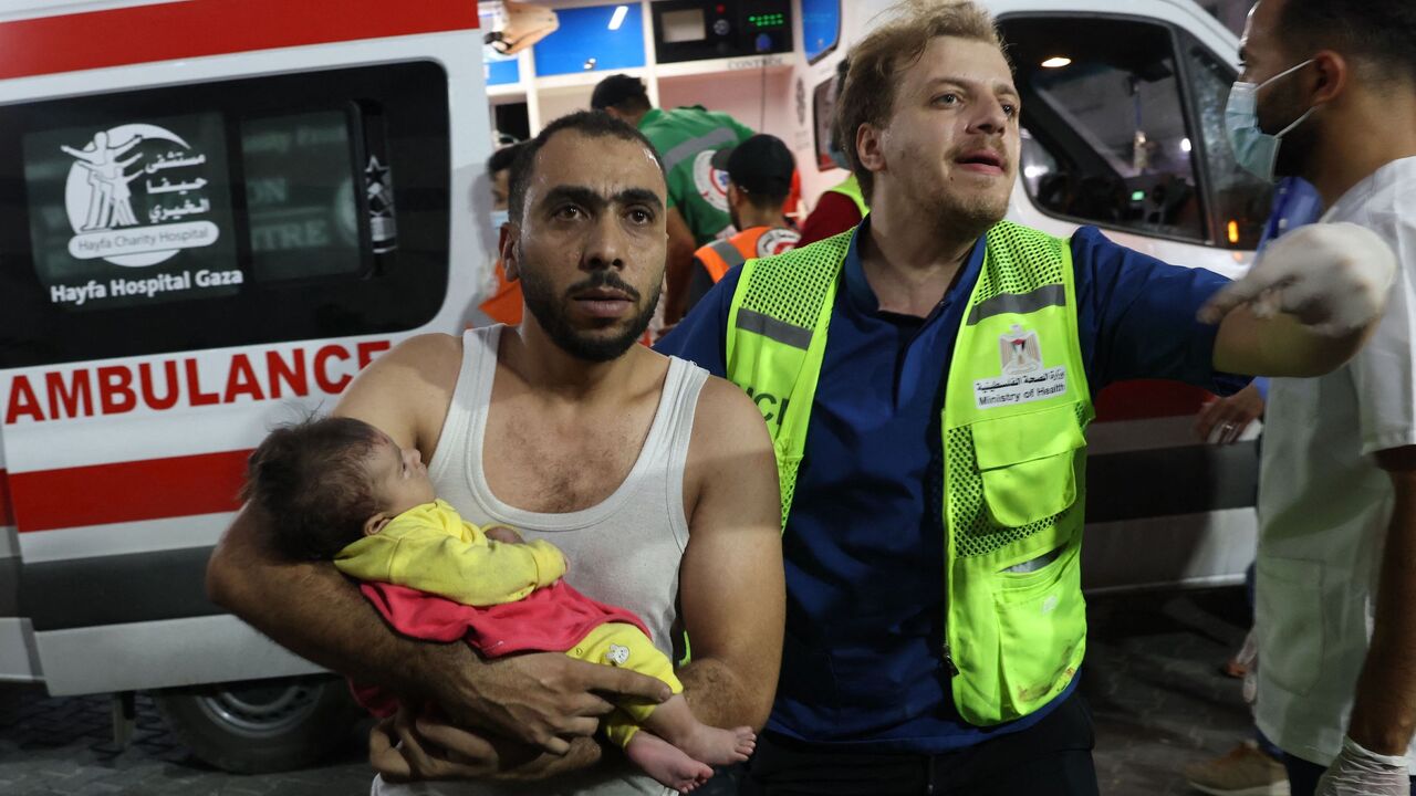 A man transports an injured Palestinian baby into Al-Shifa Hospital in Gaza City following an Israeli airstrike, October 11, 2023.