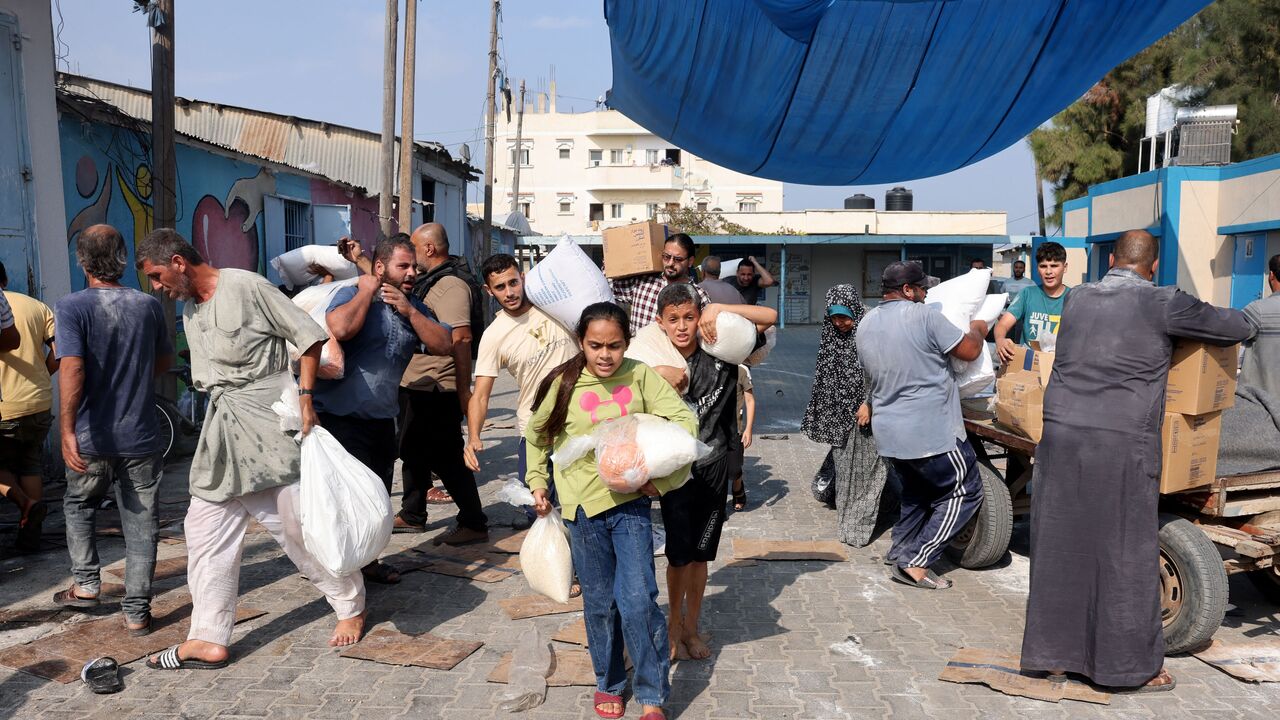  Palestinians storm a UN-run aid supply center, that distributes food to displaced families following Israel's call for more than one million residents in northern Gaza to move south for their safety, in Deir al-Balah on October 28, 2023,