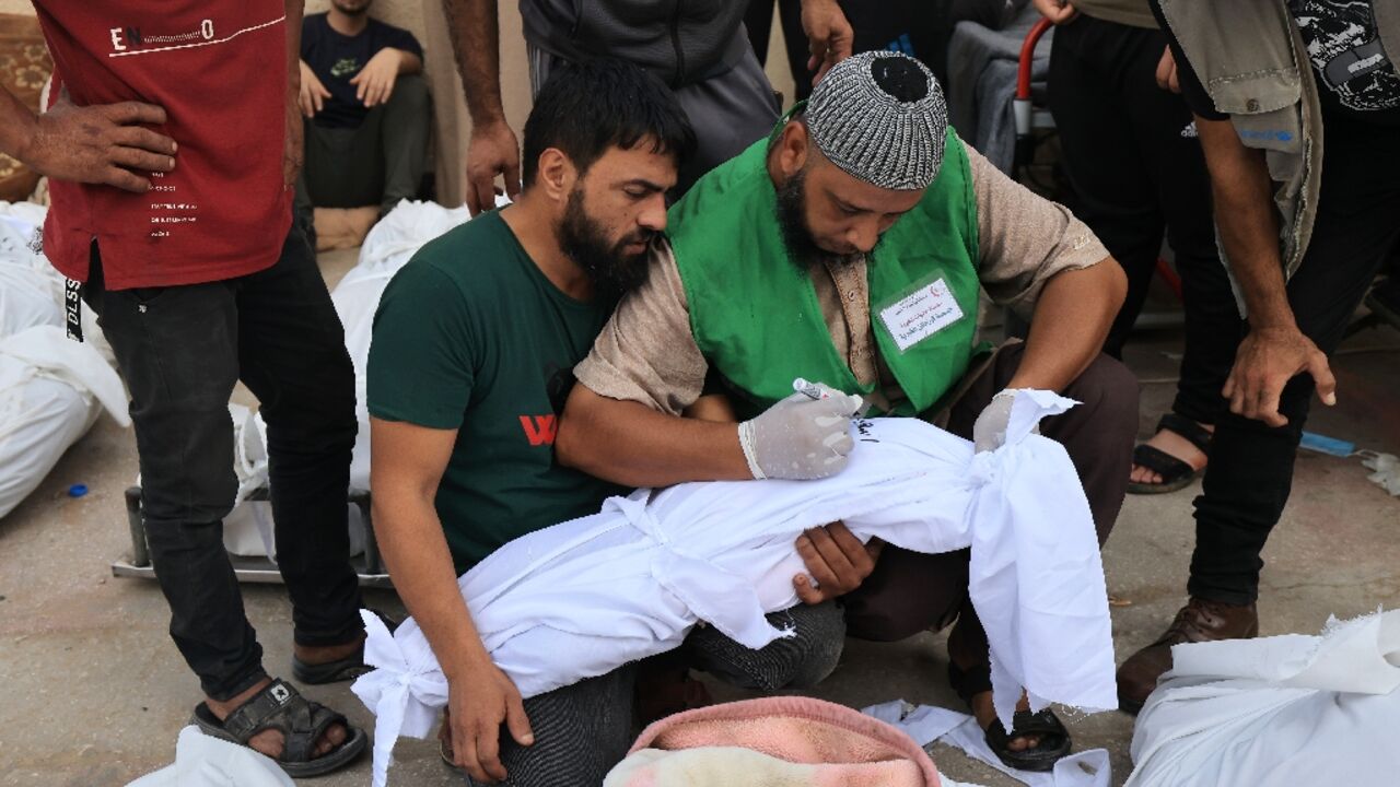 A man writes the name on the shroud of a child killed in an Israeli strike on Deir Balah in central Gaza A man writes the name on the shroud of a child killed in an Israeli strike on Deir Balah in central Gaza