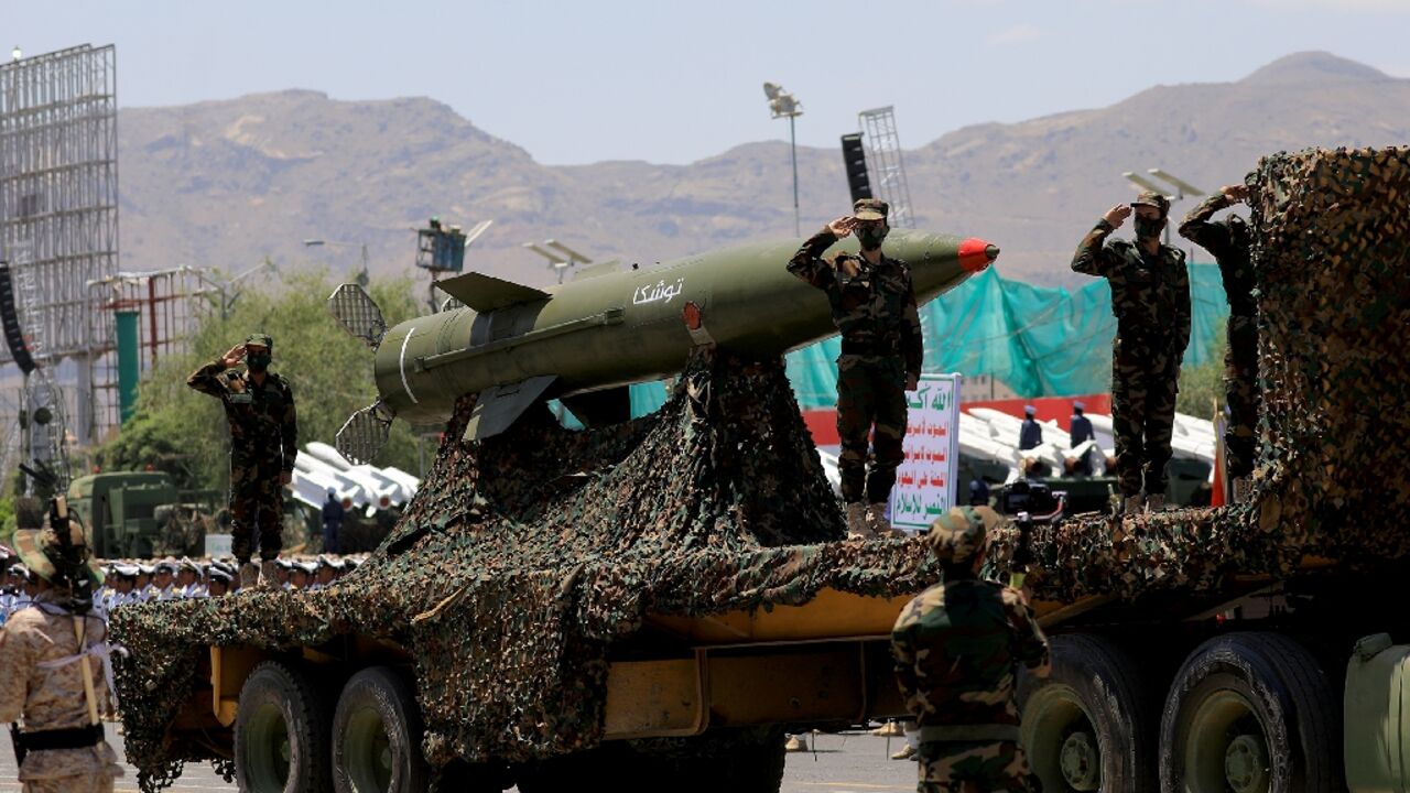 Huthi soldiers salute next to a missile during a parade in Sanaa in September