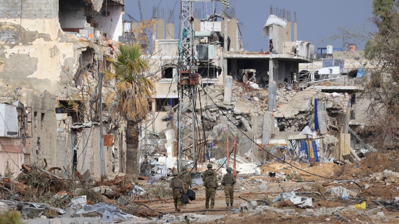 Israeli troops walk past destroyed buildings along the north-south Salaheddine road in Gaza Israeli troops walk past destroyed buildings along the north-south Salaheddine road in Gaza