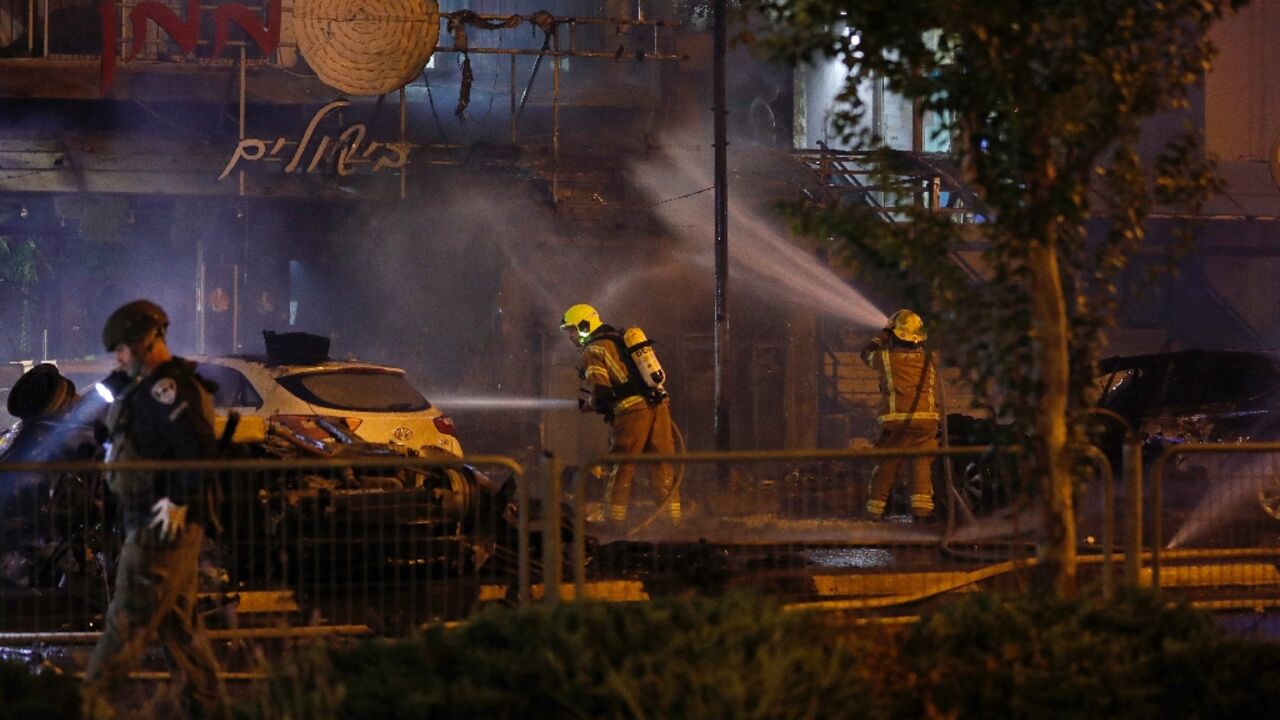 Israeli firefighters douse vehicles following a rocket attack on the northern town of Kiryat Shmona close to the Lebanese border