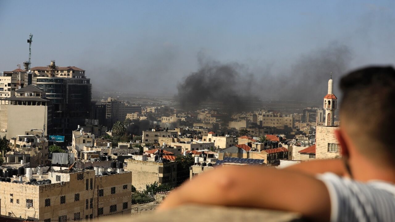 A child watches smoke rising from the Jenin Palestinian refugee camp, during clashes after an Israeli raid