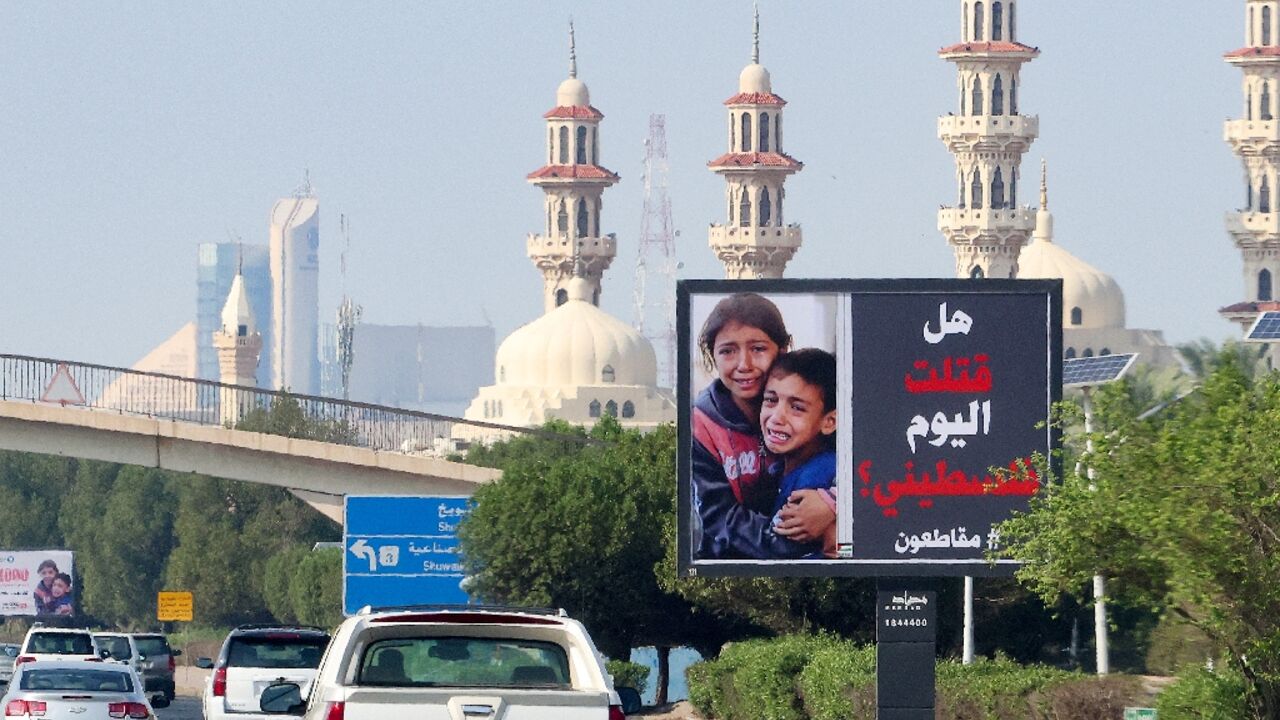 Cars drive past a billboard in Kuwait City showing Palestinian children and the slogan: "Have you killed a Palestinian today? #boycott"