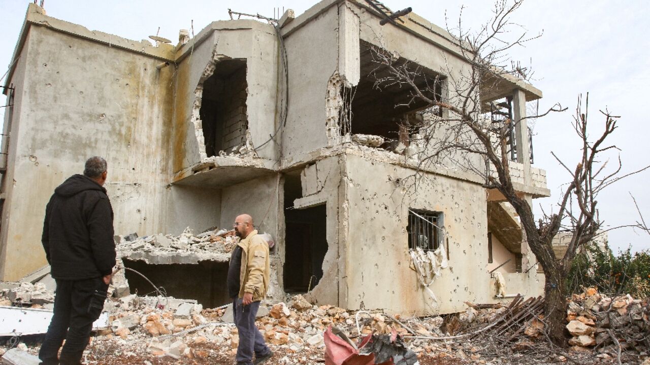 Lebanese farmer and minibus driver Abdallah Abdallah (L) inspects his damaged home in Aitaroun, southern Lebanon on November 25, 2023