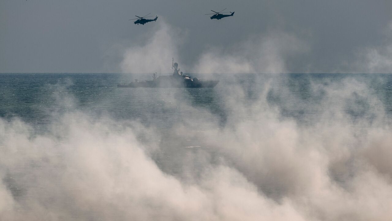 Russian army Mi-24 helicopters fly above a warship at the Turali range on the Caspian Sea coast in the Republic of Dagestan in Southern Russia on September 23, 2020 during the "Caucasus-2020" military drills gathering China, Iran, Pakistan and Myanmar troops, along with ex-Soviet Armenia, Azerbaijan and Belarus. - Up to 250 tanks and around 450 infantry combat vehicles and armoured personnel carriers will take part in the September 21 to 26 land and naval exercises that will involve 80,000 people including 