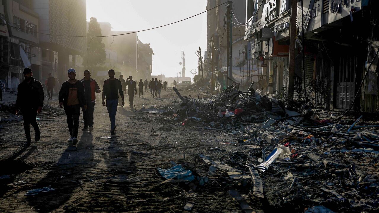 Palestinians walk amid the rubble of destroyed buildings in Gaza City on the northern Gaza strip following weeks of Israeli bombardment, as a four-day ceasefire took effect on Nov. 24, 2023.