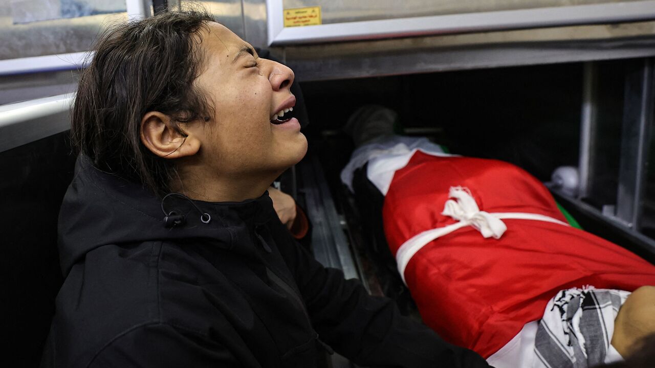 A child mourns over the body of one of five people killed in the occupied West Bank city of Jenin during an overnight Israeli incursion, at the morgue of a hospital on November 26, 2023. Five people were killed by Israeli army fire in Jenin, the Palestinian health ministry said, during an incursion by a large number of armoured vehicles into the city, which was recently the scene of the deadliest Israeli raid in the West Bank in almost 20 years. (Photo by Zain JAAFAR / AFP) (Photo by ZAIN JAAFAR/AFP via Get