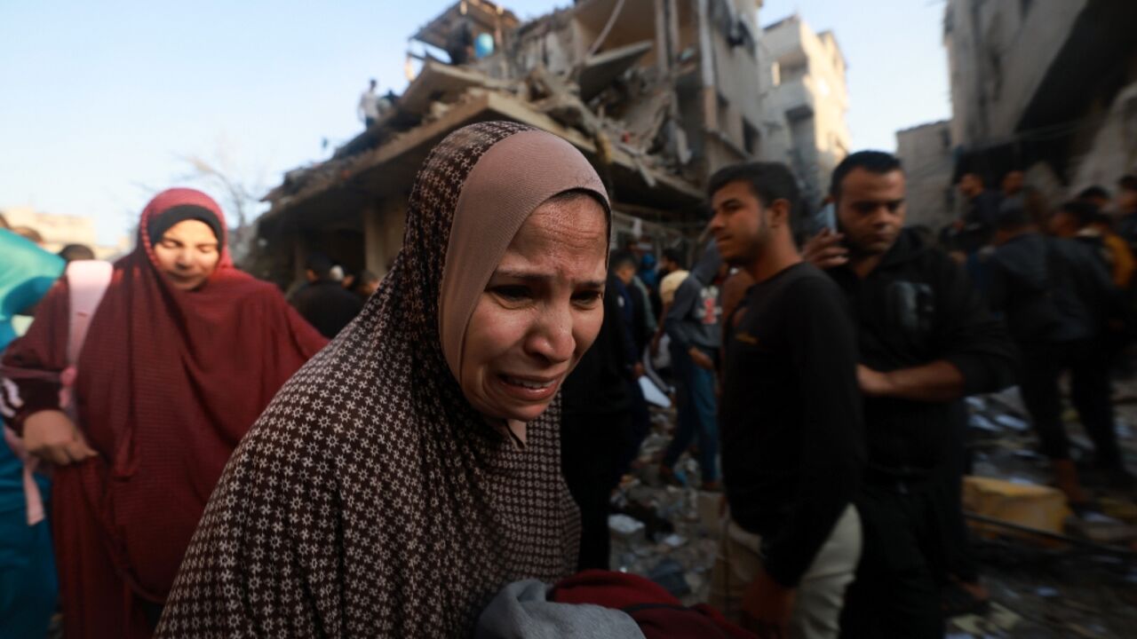 A Palestinian woman reacts as people check the rubble of a building destroyed in the Rafah refugee camp as Israeli air strikes resumed after a truce between Israel and Hamas militants expired