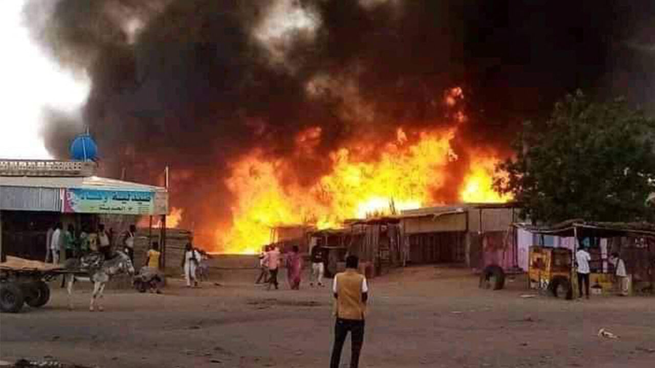 TOPSHOT - A man stands by as a fire rages in a livestock market area in al-Fasher, the capital of Sudan's North Darfur state, on September 1, 2023, in the aftermath of bombardment by the paramilitary Rapid Support Forces (RSF). The conflict between Sudan's army under General Abdel Fattah al-Burhan and the RSF commanded by Mohamed Hamdan Daglo spread in late August 2023 to North Darfur state, with at least 27 localities burned down by the RSF and allied Arab militias, according to the Humanitarian Research L