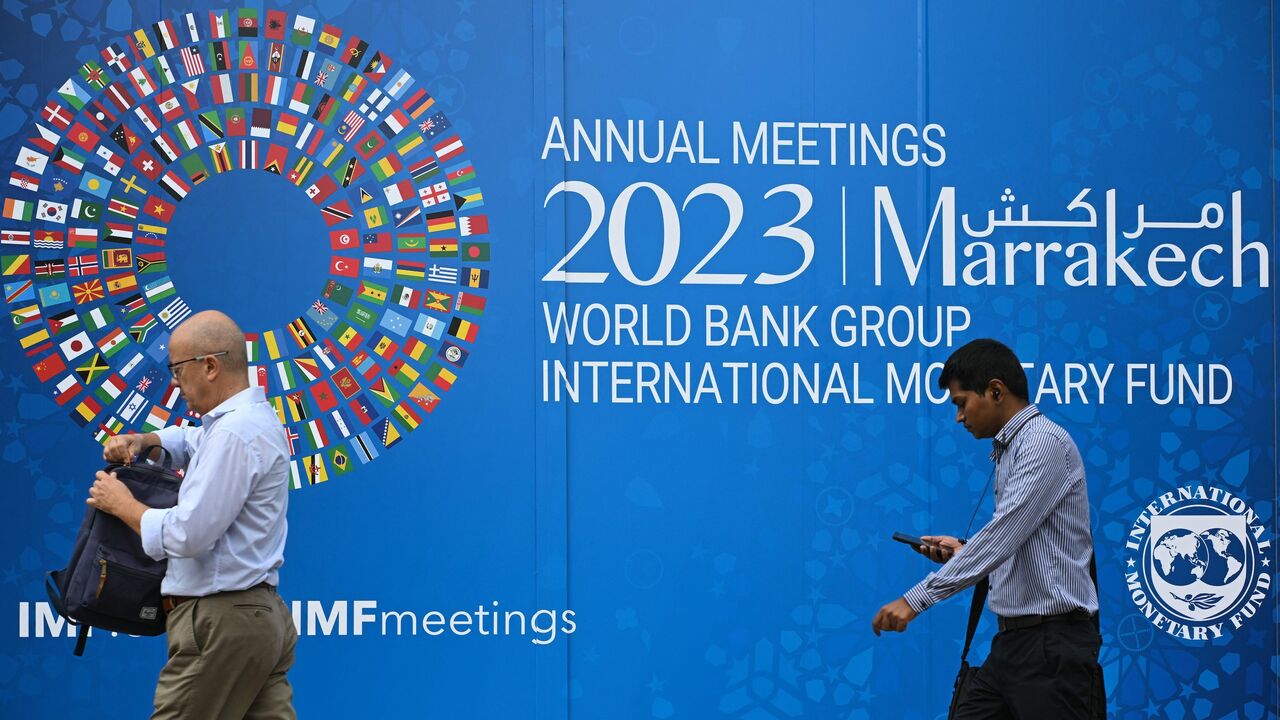 Pedestrians walk past a billboard announcing the World Bank Group and International Monetary Fund annual meetings, where the organizations looked to scale up and retool to pursue ambitious global climate goals, Washington, DC, Oct. 5, 2023.