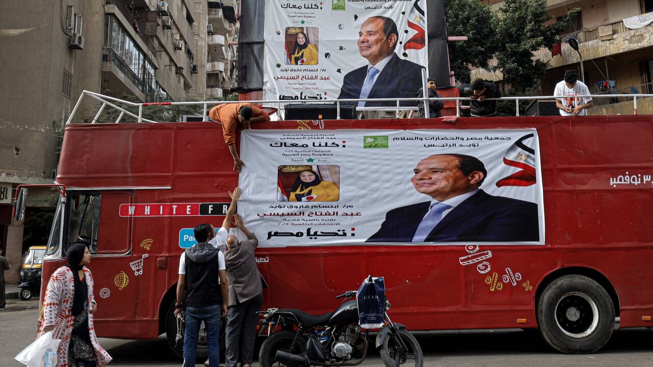 Supporters hang a campaign banner of Egypt's President Abdel Fattah al-Sisi at a bus on a street in Cairo on December 7, 2023, ahead of the country's presidential election.