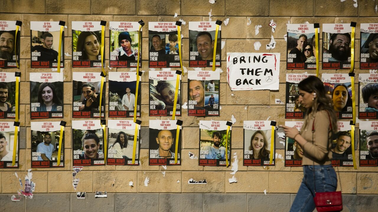 A woman walks by a wall with photos of hostages taken to the Gaza Strip during the deadly Oct 7 Hamas attack on Dec. 20, 2023, in Tel Aviv, Israel. 