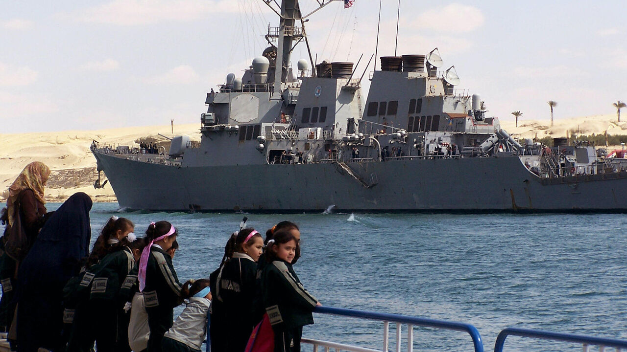 Egyptian school children stand on a pier in the port town of Ismalia, 120 kilometers northeast of Cairo, as the US guided-missile destroyer USS Mahan transits the Suez from the Red Sea towards the Mediterranean on its way back home after a six-month counter-piracy operation around the Gulf of Aden, Arabian Gulf, Indian Ocean and Red Sea.