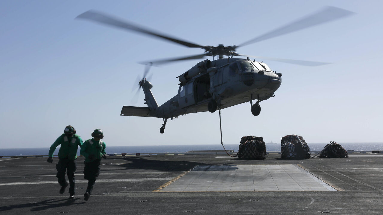 In this handout photo provided by the U.S. Navy, Logistics Specialist 1st Class Ousseinou Kaba (left), from Silver Spring, Md., and Logistics Specialist Seaman Abigail Marshke, from Flint, Mich., attach cargo to an MH-60S Sea Hawk helicopter from the "Nightdippers" of Helicopter Sea Combat Squadron (HSC) 5 from the flight deck of the Nimitz-class aircraft carrier USS Abraham Lincoln (CVN 72) May 10, 2019 in the Red Sea. 