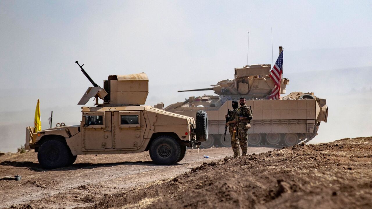 Fighters of the Syrian Democratic Forces (SDF) stand near a US Bradley Fighting Vehicle (BFV) during a joint military exercise with forces of the US-led "Combined Joint Task Force-Operation Inherent Resolve" coalition against the Islamic State (IS) group in the countryside of the town of al-Malikiya (Derik in Kurdish) in Syria's northeastern Hasakah province on Sept. 7, 2022.