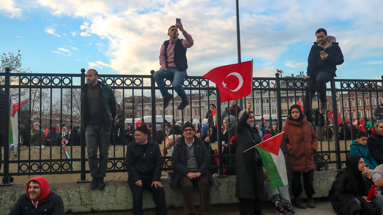 01/01/2024, Istanbul, Turkey. People sits on the iron fences to watch and participate the solidarity march. Thousands gathered in Istanbul Galata Bridge in a demonstration expressing solidarity with the Palestinian people amid the ongoing conflict between Israel and Palestine. (Photo by Ilker Eray / Middle East Images / Middle East Images via AFP) (Photo by ILKER ERAY/Middle East Images/AFP via Getty Images)