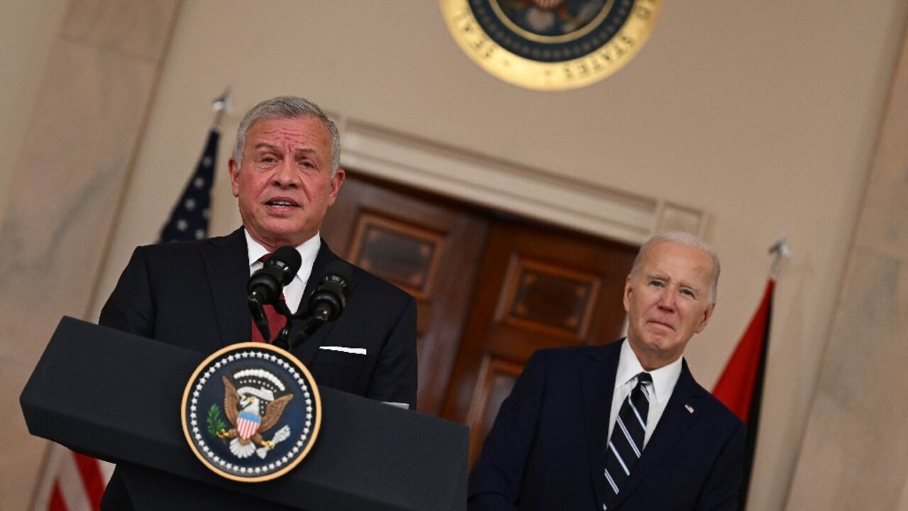 King Abdullah II of Jordan speaks to the press as US President Joe Biden looks on in the Cross Hall of the White House