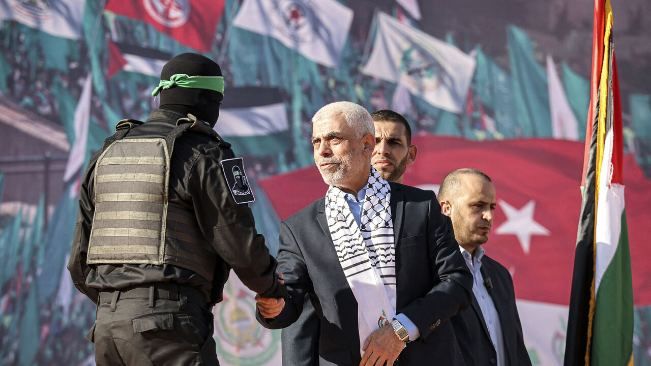 Yahia al-Sinwar (C), Gaza Strip chief of the Palestinian Islamist Hamas movement, shakes hands with a masked fighter of Hamas' Qassam Brigades during a rally marking the 35th anniversary of the group's foundation, in Gaza City on December 14, 2022. - Hamas will end talks on securing a prisoner exchange with Israel unless there is progress soon, the militant group's leader in the Gaza Strip said on December 14. Since Israel's 2014 invasion of the Gaza Strip, the Islamist group has held the bodies of Israeli 