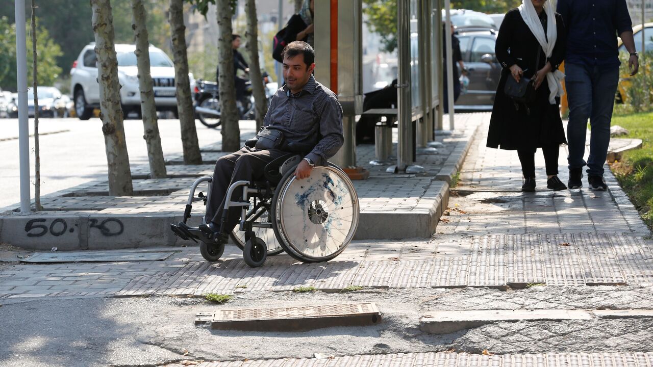 Computer teacher Behnam Soleimani makes his way along an uneven sidewalk in Tehran, July 17, 2017.