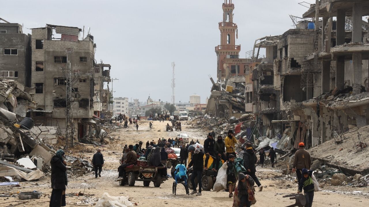 Palestinians leave the southern Gaza City of Khan Yunis, which saw heavy fighting, after returning briefly to check on what remains of their homes 