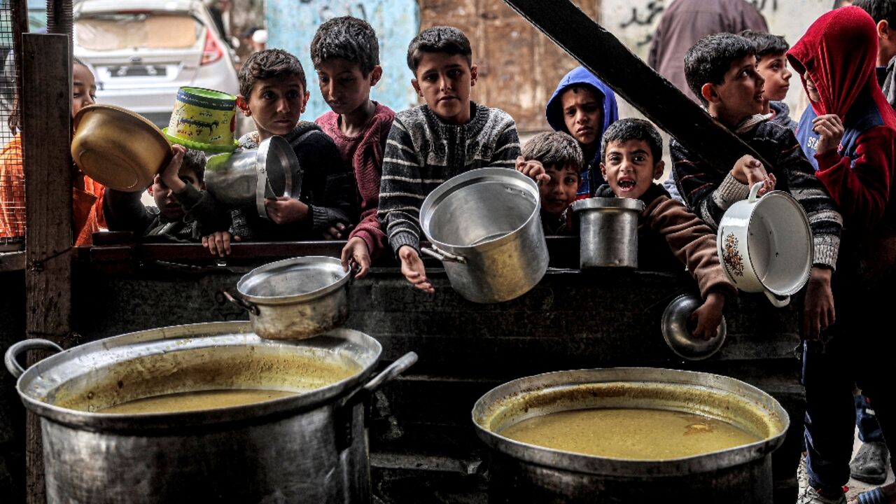 Children queue for food ahead of iftar meal to break the daily fast on Ramadan, in southern Gaza's Rafah