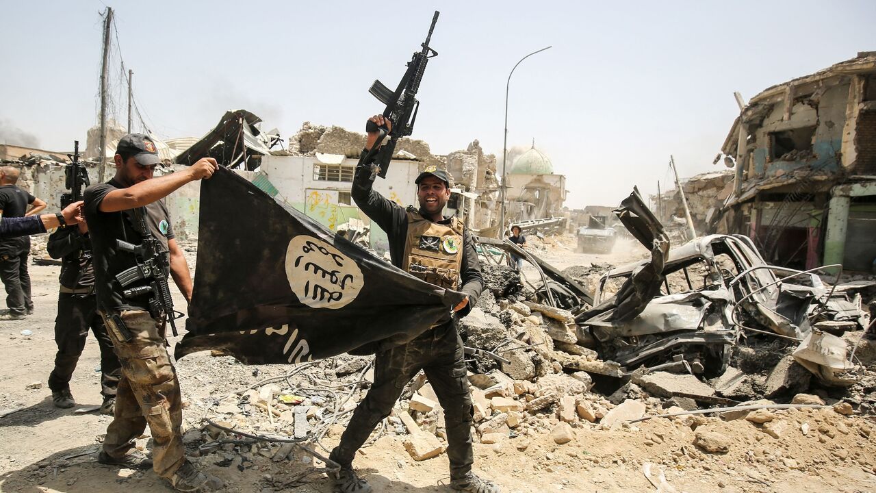 Members of the Iraqi Counter-Terrorism Service (CTS) cheer as they carry upside-down a black flag of the Islamic State (ISIS) group in the Old City of Mosul on July 2, 2017.
