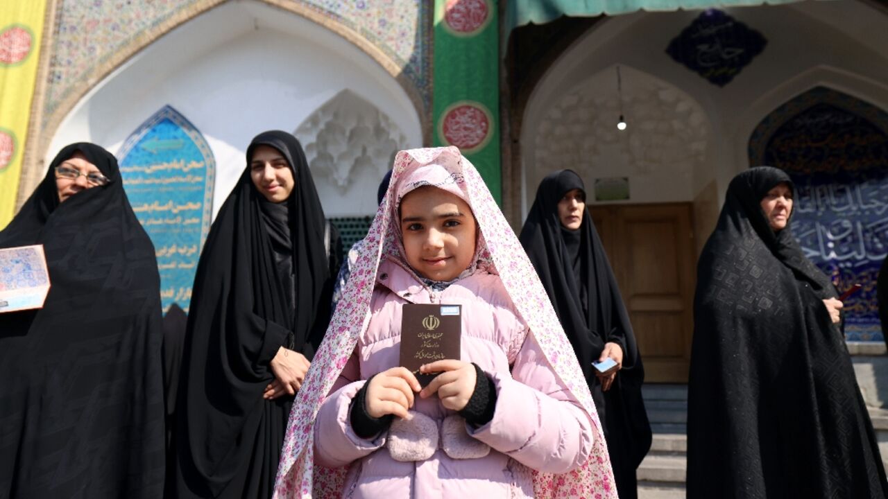 An Iranian child shows the document of a family member as women queue in front of a polling station to cast their ballots in Tehran An Iranian child shows the document of a family member as women queue in front of a polling station to cast their ballots in Tehran