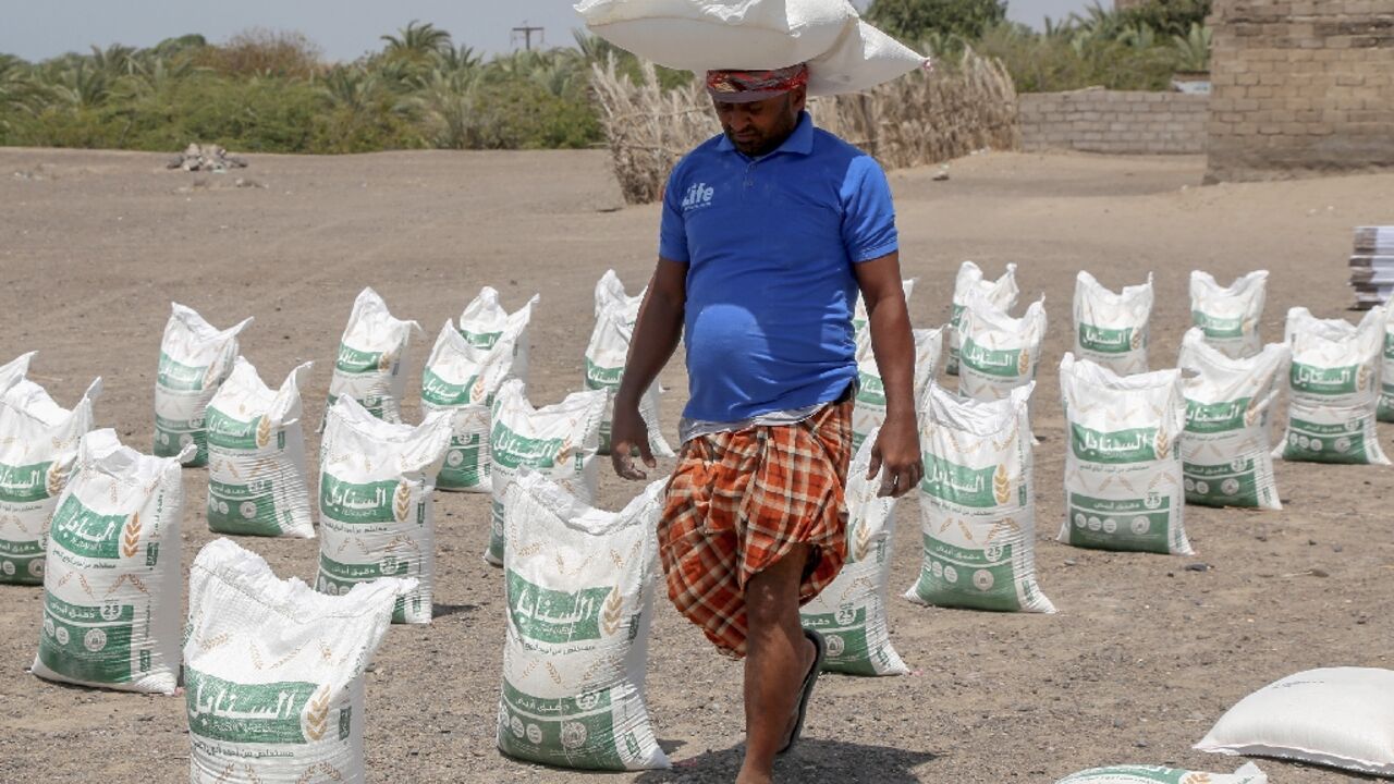 Workers unload aid sacks donated by Yemeni expatriates in the United States for distribution during Ramadan