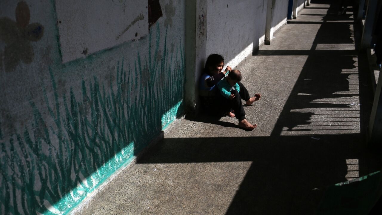 A girl brushes the hair of her sibling at a Gaza school now housing displaced families A girl brushes the hair of her sibling at a Gaza school now housing displaced families
