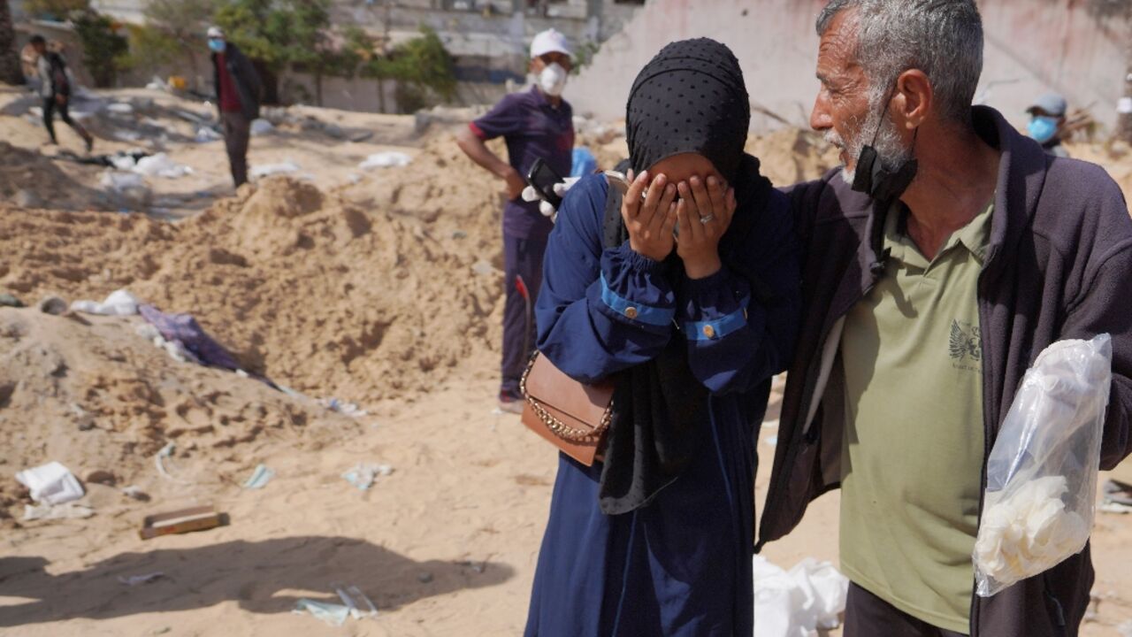 Palestinians react after the body of a relative was found buried at the Nasser hospital in southern Gaza