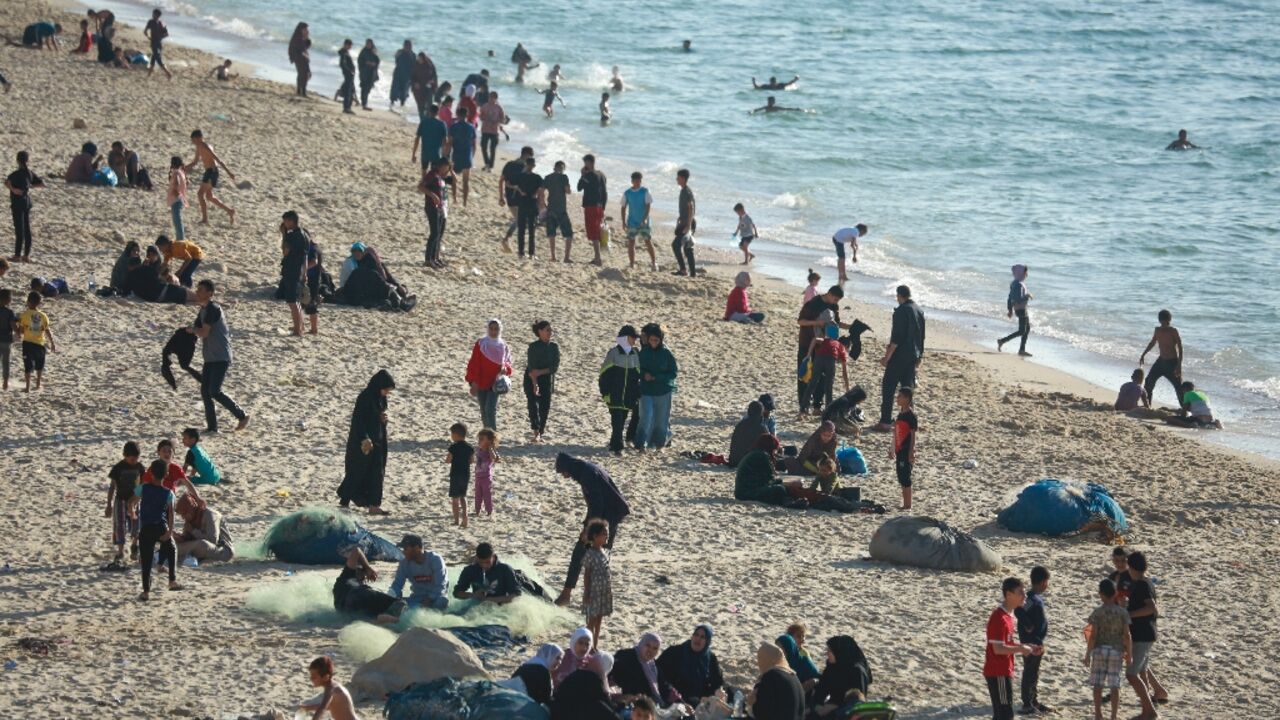 Children paddled in the sea and their friends played ball games on the sand  -- but Gaza's war was never far away