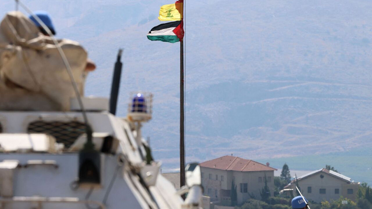 The Palestinian flag and the flag of Hezbollah wave in the wind on a pole as peacekeepers from the United Nations Interim Force in Lebanon (UNIFIL) patrol the border area between Lebanon and Israel on Hamames hill in the Khiyam area of southern Lebanon, on Oct. 13, 2023. 