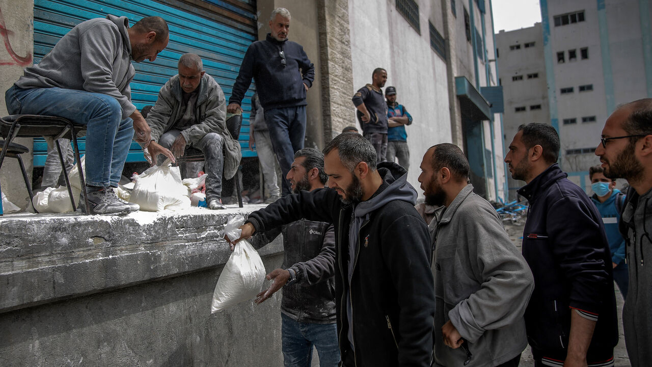 A man hands out bags of flour during the distribution of humanitarian aid in Gaza City on March 17, 2024, amid ongoing battles between Israel and the militant group Hamas. 