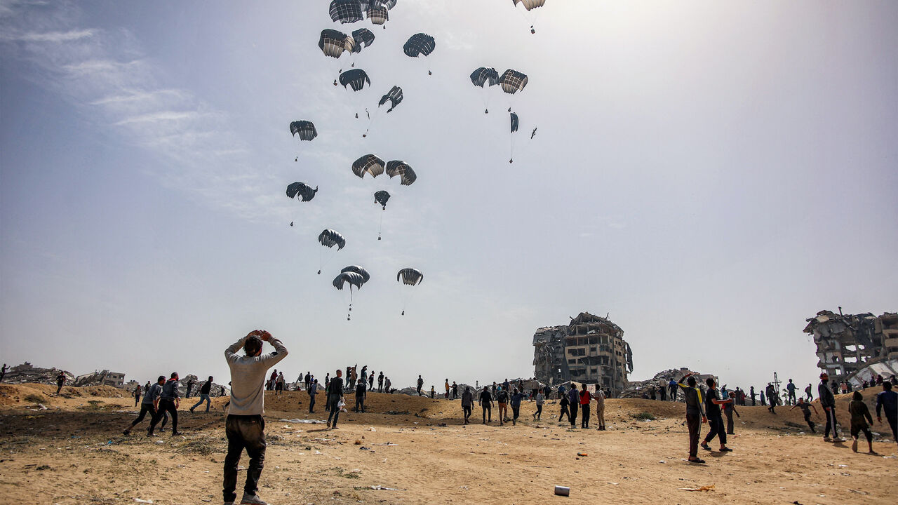 People rush to landing humanitarian aid packages dropped over the northern Gaza Strip on April 23, 2024 amid the ongoing conflict in the Palestinian territory between Israel and the militant group Hamas.