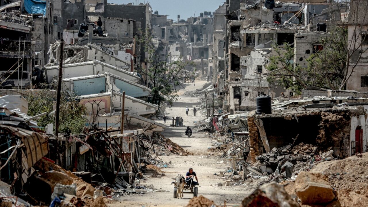 Palestinians walk on a road lined with destroyed buildings in Khan Yunis, where intense fighting raged in February 2024