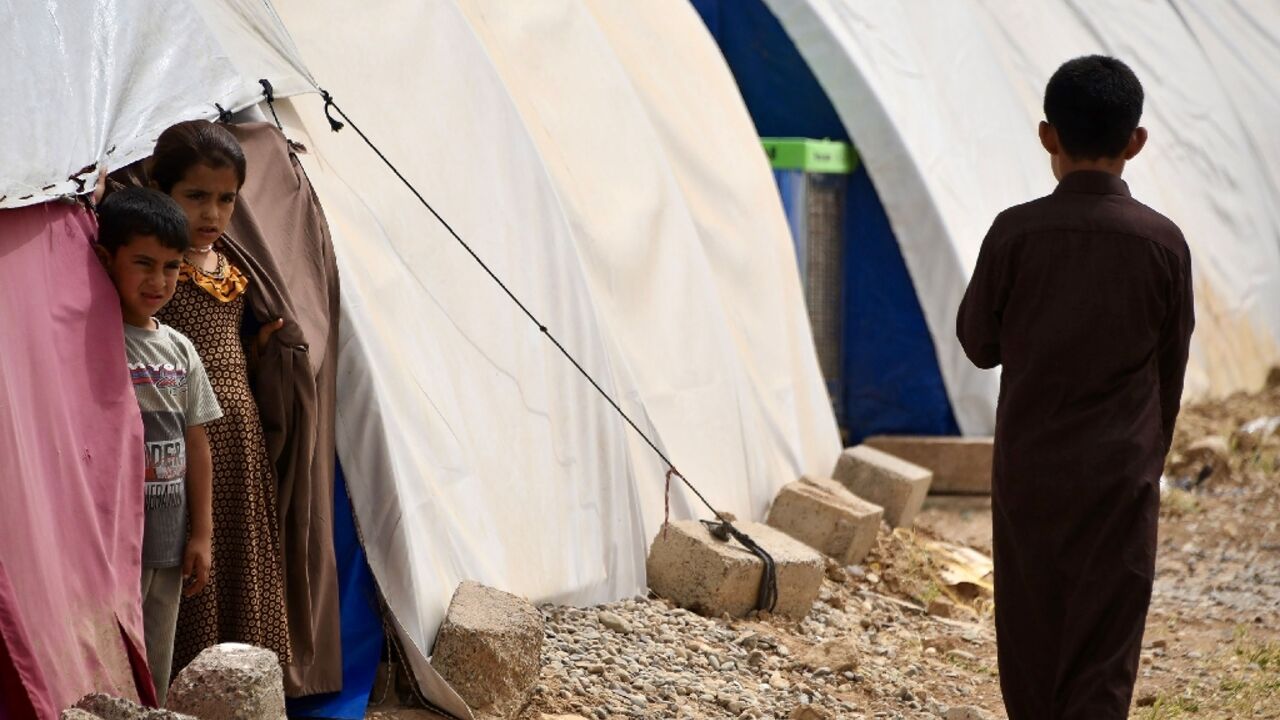 Children stand by tents in April 2024 at the Al-Jadaa camp south of Mosul which houses Iraqi families who have been repatriated from Syria's Al-Hol camp