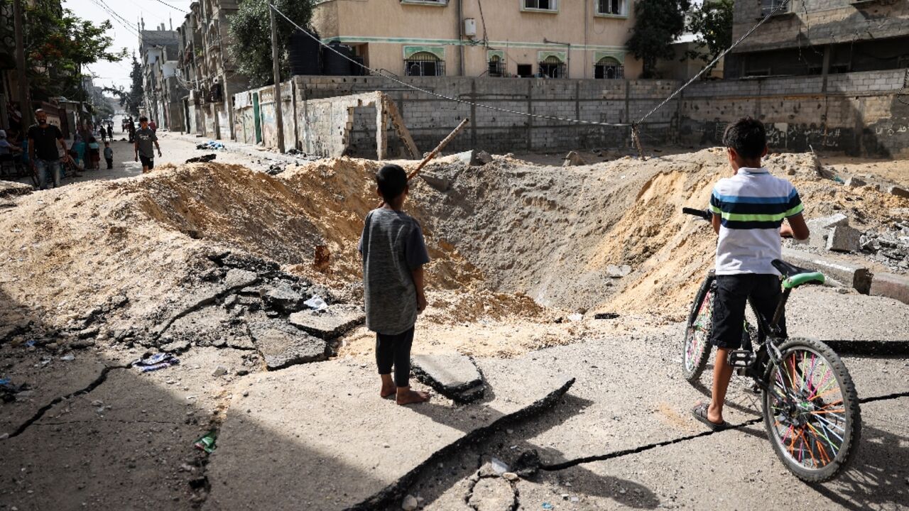 Children stand near a crater caused by Israeli bombardment in a street in Rafah in the southern Gaza Strip Children stand near a crater caused by Israeli bombardment in a street in Rafah in the southern Gaza Strip