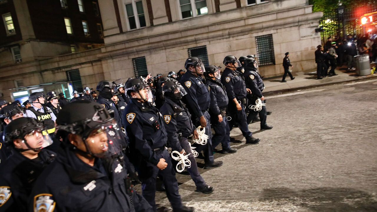 NYPD officers in riot gear march onto Columbia University campus, where pro-Palestinian students are barricaded inside a building and have set up an encampment, in New York City on April 30, 2024. Columbia University normally teems with students, but a "Free Palestine" banner now hangs from a building where young protesters have barricaded themselves and the few wandering through campus generally appear tense. Students here were among the first to embrace the pro-Palestinian campus encampment movement, whic