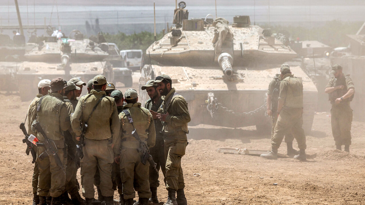 Israeli army soldiers huddle together before a main battle tank positioned in southern Israel near the border with the Gaza Strip on May 9, 2024, amid the ongoing conflict in the Palestinian territory between Israel and the Hamas movement. (Photo by AHMAD GHARABLI / AFP) (Photo by AHMAD GHARABLI/AFP via Getty Images)