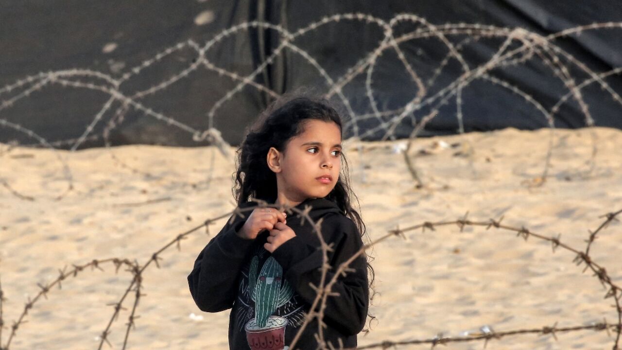 A girl stands behind barbed wire at a camp for displaced Palestinians in Rafah in the southern Gaza Strip on April 30, 2024